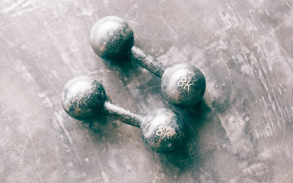 A pair of iron 8 kg dumbbells on a concrete floor